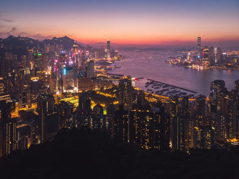 Illuminated modern buildings in city against sky at night