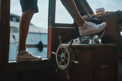 Low section of man standing on boat controls at harbor