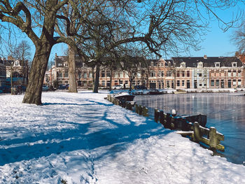 Canal amidst trees and buildings during winter