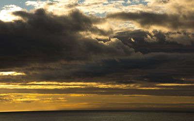 Scenic view of sea against dramatic sky during sunset