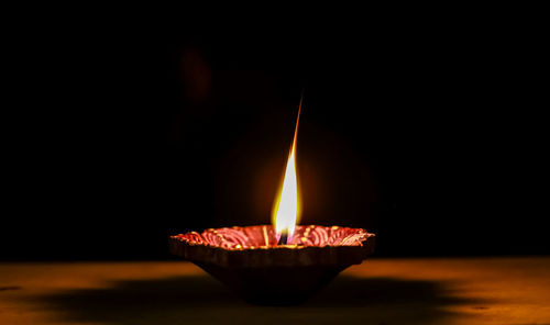 Close-up of lit candle in the dark