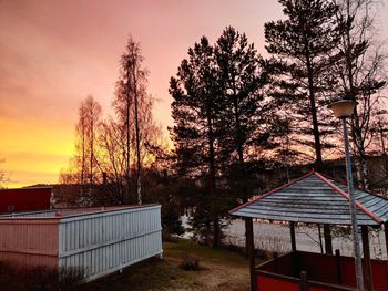 Building and trees on field against sky at sunset