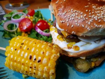 Close-up of burger and corn in plate on table