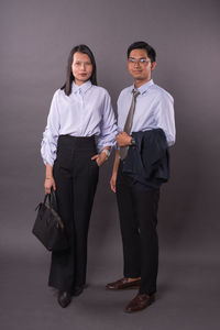 Portrait of a young couple standing against wall