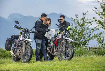 Three friends looking at map on motorcycle trip