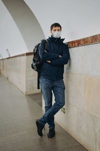 Full length of young man standing against wall