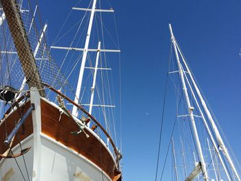 Low angle view of sailboat moored at harbor against clear blue sky