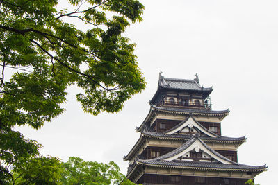 Low angle view of trees and building against sky