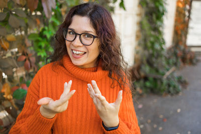 Portrait of young woman standing against trees