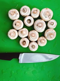 Directly above shot of wet mushrooms by kitchen knife on green cutting board