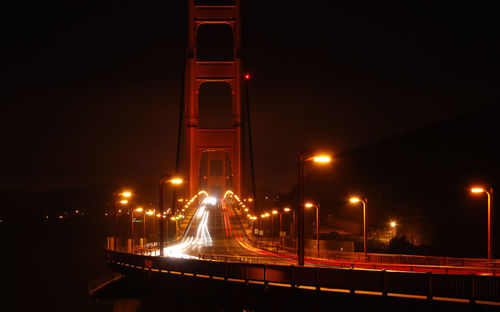 Light trails on bridge against sky at night