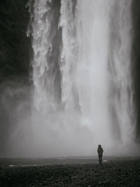 Rear view of woman standing against waterfall