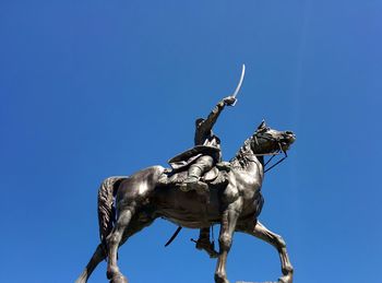 Low angle view of statue against clear blue sky