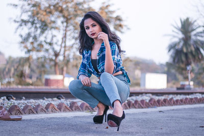 Portrait of teenage girl crouching by railroad track