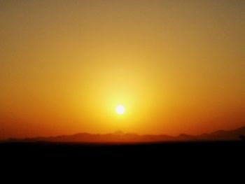 Scenic view of silhouette landscape against orange sky