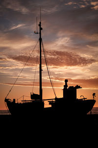 Silhouette sailboats moored on sea against sky during sunset