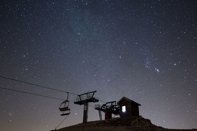 Low angle view of ski lift against sky at night