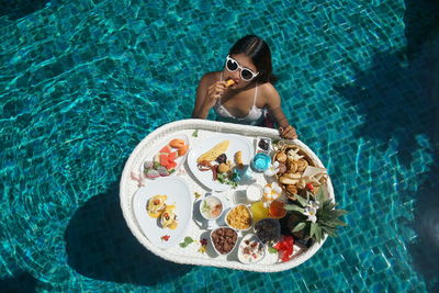 High angle view of woman having food in swimming pool