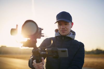 Portrait of man photographing against sky during sunset