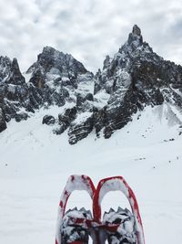 Low section of person wearing ski boots on snowcapped mountain