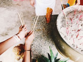 Cropped hands of woman holding incense sticks at temple