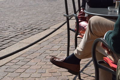 Low section of woman sitting on seat in street