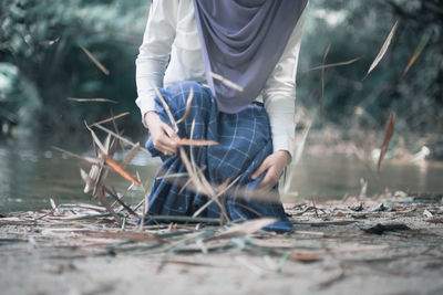 Low section of man holding umbrella on field