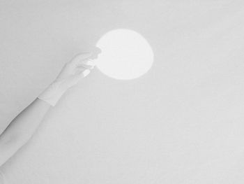 Shadow of hand holding glass against white background