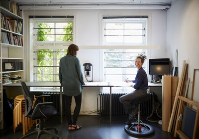 Smiling female architect with coworker at table in office