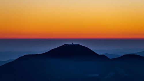 Scenic view of silhouette mountains against romantic sky at sunset