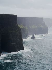 Rock formation by sea against sky