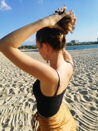 Young woman at beach against sky