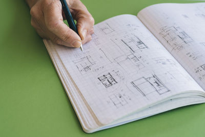 Architect drawing sketches on notebook on green table