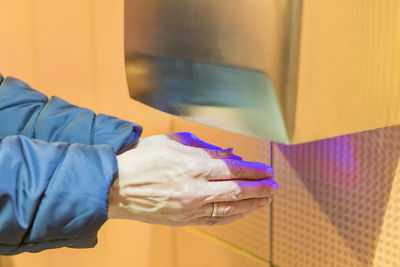 Close-up of woman drying hands in restroom