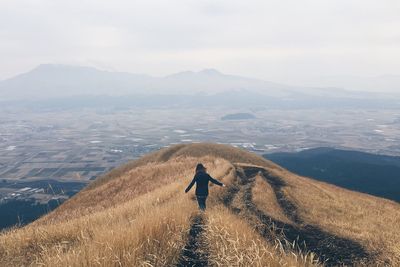 Rear view of man standing on mountain against sky