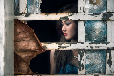 Beautiful woman seen through weathered window frame