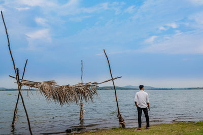 Rear view of man standing by sea against sky