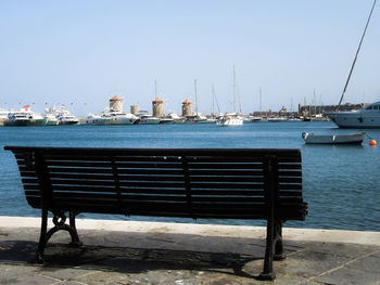 Boats moored at harbor against clear sky