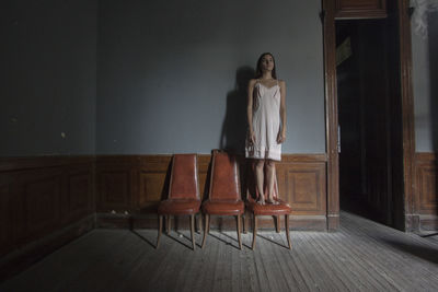 Woman standing on chair at home