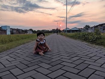 Toddler sitting on lonely street during evening time 