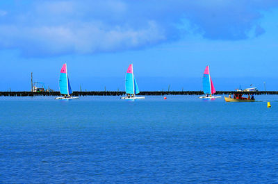 Sailboats on sea against blue sky