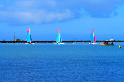 Sailboats on sea against blue sky