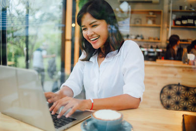 Smiling businesswoman using laptop at cafe