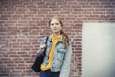 Blond teenage girl against brick wall