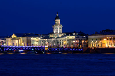 Illuminated building against blue sky at night