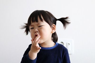 Close-up portrait of girl standing against wall