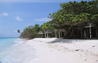 Abandoned structures on a beach against blue sky