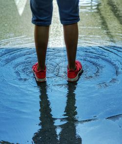 Low section of man standing on puddle