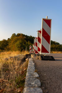 Empty road amidst trees against clear sky