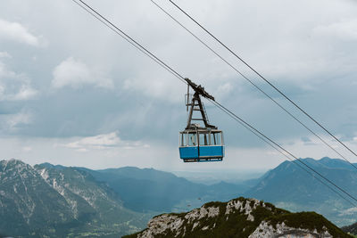 Overhead cable car over mountains against sky